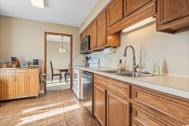 kitchen with stainless steel appliances, sink, hanging light fixtures, and light tile patterned floors