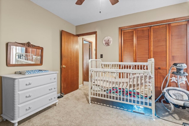 carpeted bedroom featuring a nursery area, a closet, and ceiling fan