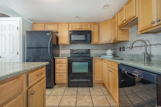 kitchen with sink, decorative backsplash, light tile patterned floors, black appliances, and light stone countertops