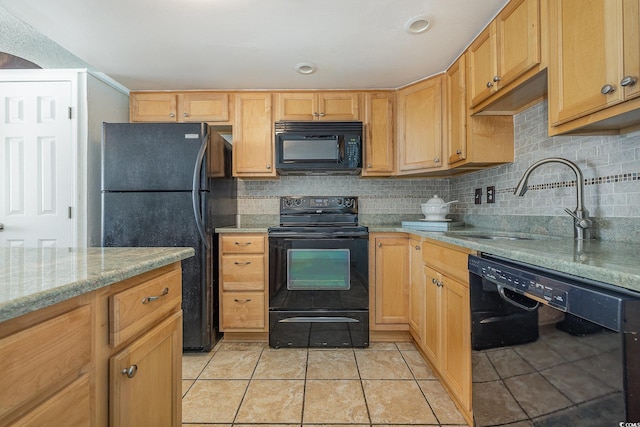 kitchen featuring light tile patterned floors, tasteful backsplash, light stone countertops, black appliances, and a sink