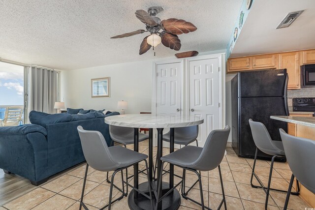 dining space featuring light tile patterned flooring, ceiling fan, and a textured ceiling