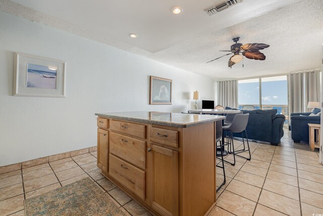 kitchen featuring a kitchen bar, a wall of windows, a textured ceiling, and a kitchen island