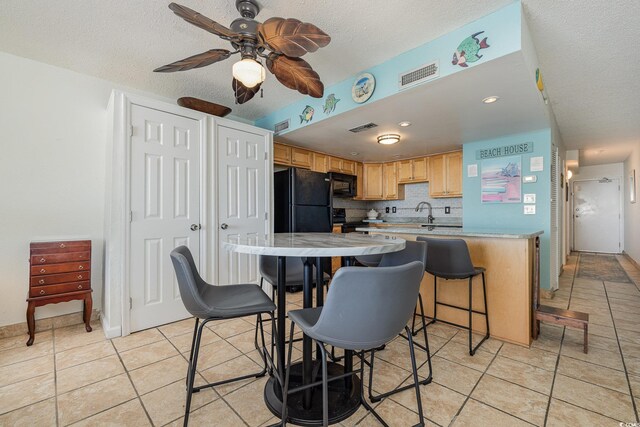 kitchen featuring decorative backsplash, black appliances, a textured ceiling, and light tile patterned flooring