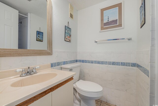 bathroom featuring tile walls, tile patterned flooring, vanity, a textured ceiling, and toilet