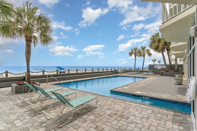 view of pool featuring a water view and a patio area