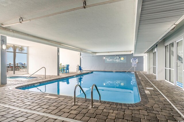 view of swimming pool featuring a patio and an indoor hot tub