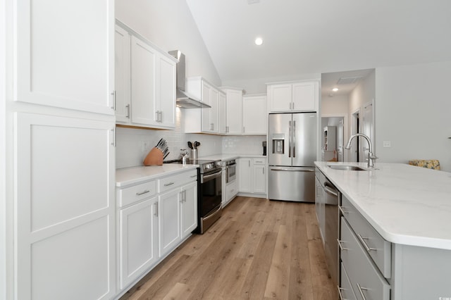 kitchen with wall chimney exhaust hood, sink, white cabinetry, stainless steel appliances, and backsplash