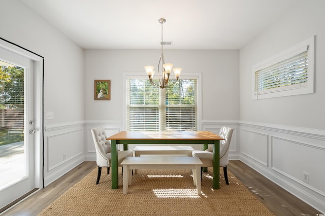 dining space with hardwood / wood-style floors and a notable chandelier