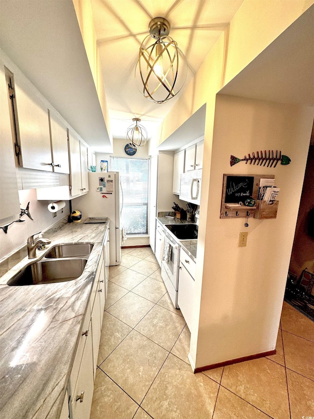 kitchen featuring sink, white appliances, light tile patterned floors, and white cabinets