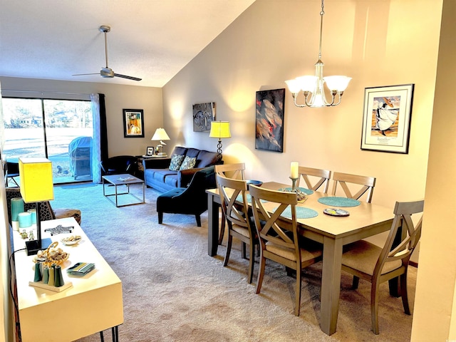 carpeted dining space featuring ceiling fan with notable chandelier and high vaulted ceiling