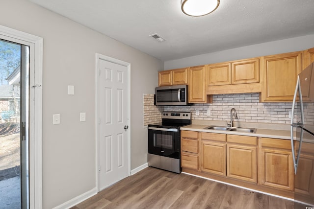 kitchen featuring sink, wood-type flooring, a textured ceiling, stainless steel appliances, and decorative backsplash