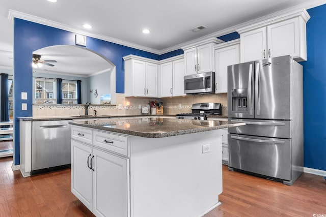 kitchen featuring dark wood-type flooring, sink, white cabinetry, a kitchen island, and stainless steel appliances