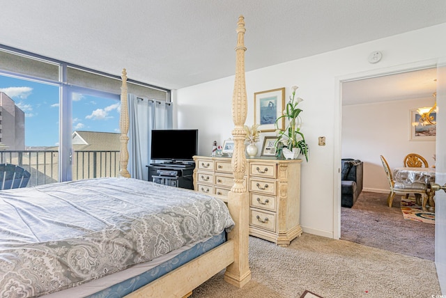 carpeted bedroom featuring access to exterior and a chandelier