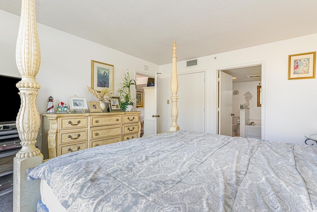 bedroom with a textured ceiling and ensuite bath