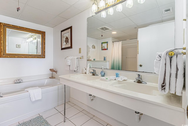 bathroom featuring dual sinks, a drop ceiling, tile patterned floors, and a tub to relax in