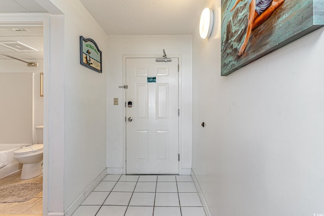 doorway with a textured ceiling and light tile patterned flooring