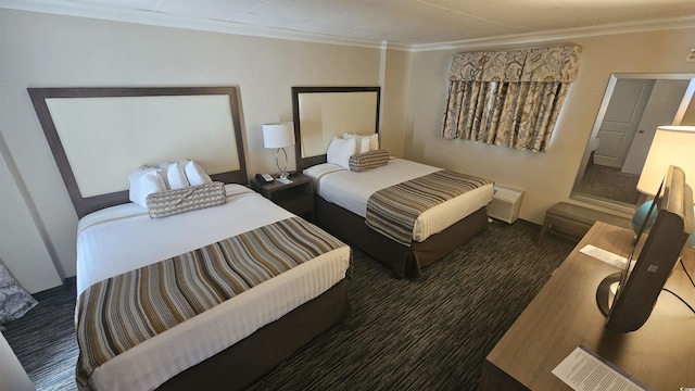 bedroom with ornamental molding and dark carpet