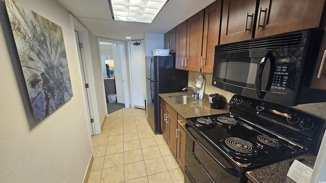 kitchen featuring sink, black appliances, dark stone counters, and light tile patterned flooring