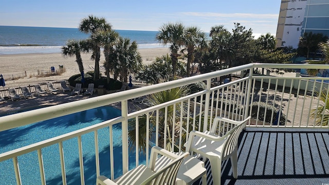 balcony with a water view and a view of the beach