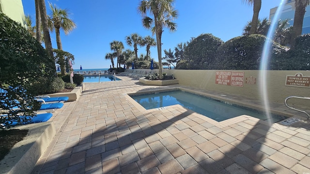 view of swimming pool featuring a patio and a water view