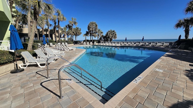 view of pool featuring a water view and a patio area