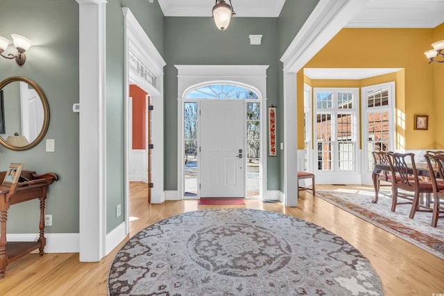 entryway featuring crown molding, light hardwood / wood-style floors, and a towering ceiling