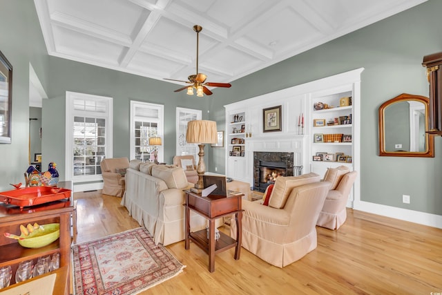 living room with a fireplace, beamed ceiling, coffered ceiling, ceiling fan, and light hardwood / wood-style flooring