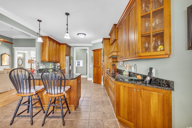 kitchen with dark stone countertops, pendant lighting, a kitchen bar, and kitchen peninsula