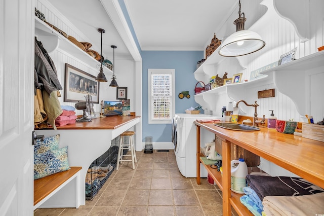 laundry area featuring ornamental molding, separate washer and dryer, sink, and light tile patterned floors