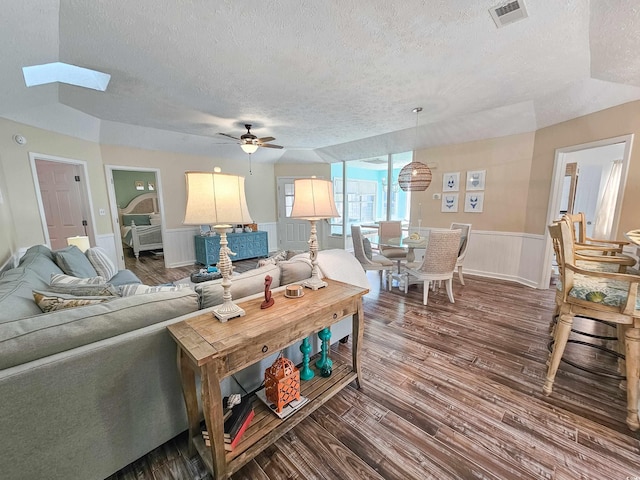 299 Lake Arrowhead Rd, Myrtle Beach, SC 29572 - living room with a textured ceiling, dark wood finished floors, ceiling fan, wainscoting, and a skylight