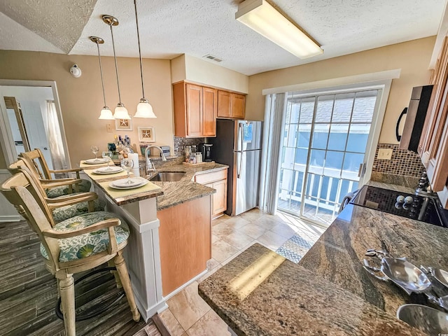 299 Lake Arrowhead Rd, Myrtle Beach, SC 29572 - kitchen featuring a textured ceiling, a peninsula, decorative backsplash, stainless steel appliances, and dark stone counters