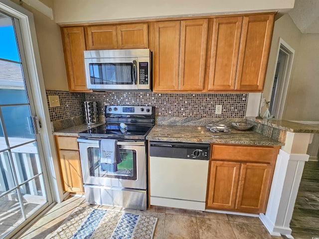299 Lake Arrowhead Rd, Myrtle Beach, SC 29572 - kitchen with stainless steel appliances, tasteful backsplash, dark stone counters, and brown cabinetry