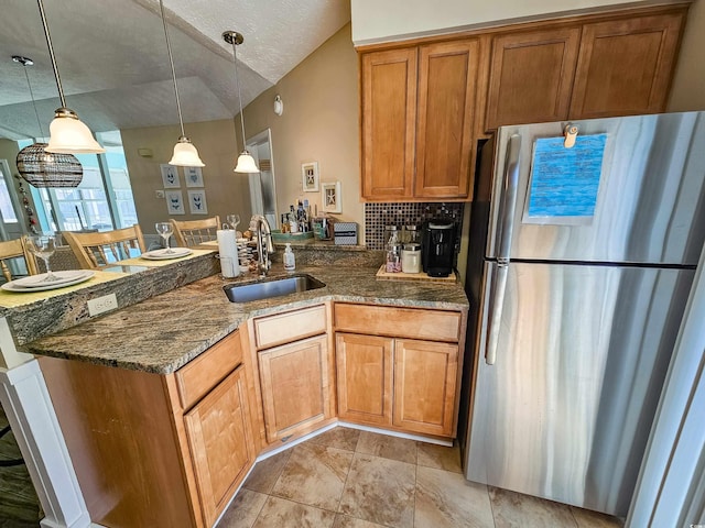 299 Lake Arrowhead Rd, Myrtle Beach, SC 29572 - kitchen featuring freestanding refrigerator, a peninsula, dark stone counters, brown cabinets, and hanging light fixtures