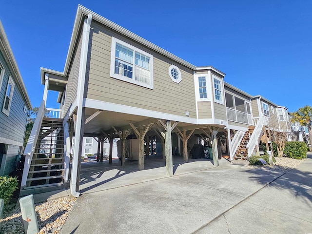 299 Lake Arrowhead Rd, Myrtle Beach, SC 29572 - view of front of home with stairway, a carport, concrete driveway, and a sunroom