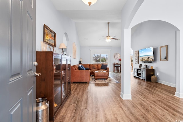 living room with ceiling fan, wood-type flooring, and high vaulted ceiling