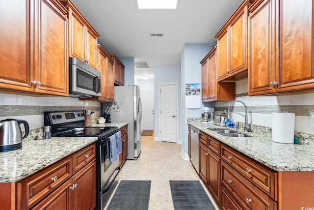 kitchen with light stone countertops, appliances with stainless steel finishes, sink, and backsplash