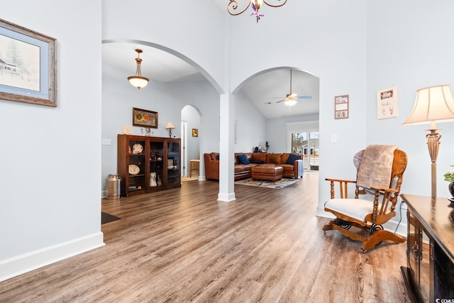 living area with wood-type flooring, ceiling fan, and a high ceiling