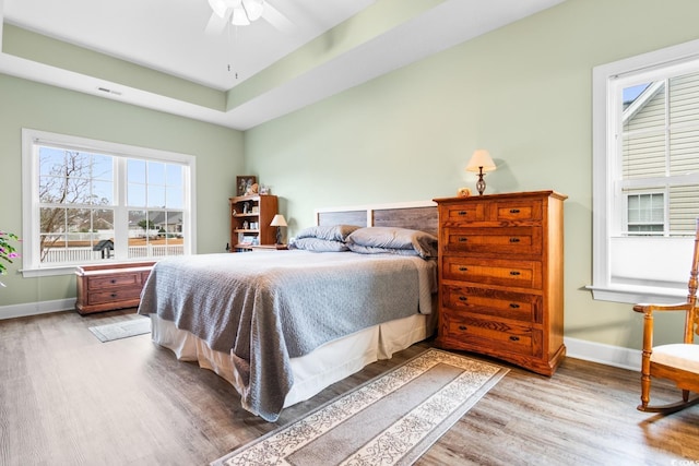 bedroom with ceiling fan, light hardwood / wood-style floors, and multiple windows