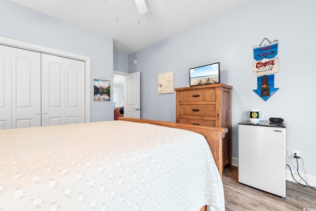 bedroom featuring hardwood / wood-style flooring, ceiling fan, fridge, and a closet