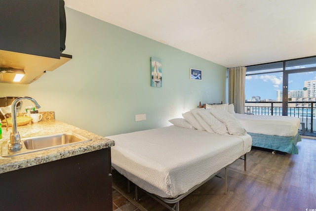 bedroom with sink, dark wood-type flooring, expansive windows, and access to exterior