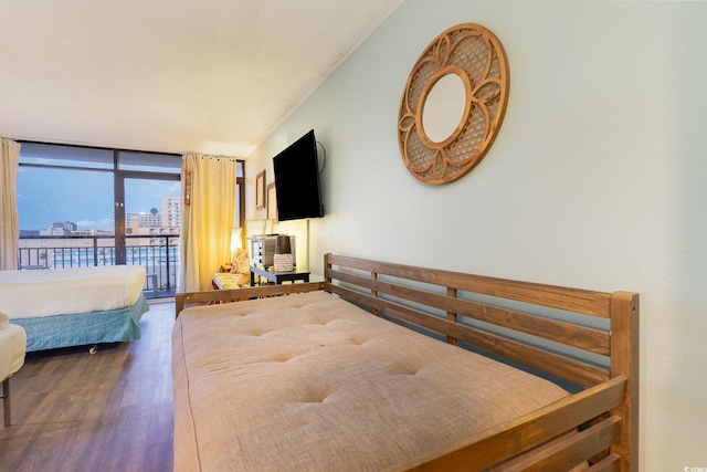 bedroom featuring dark hardwood / wood-style flooring, access to exterior, and a wall of windows