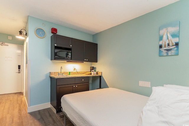 bedroom with wet bar and light hardwood / wood-style flooring