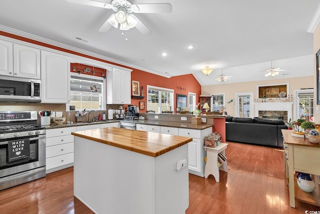 kitchen featuring white cabinetry, light wood-type flooring, appliances with stainless steel finishes, kitchen peninsula, and a kitchen island