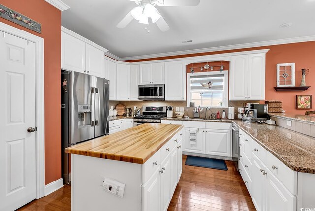 637 Sparrow Dr, Surfside Beach, SC 29575 - kitchen with butcher block countertops, a sink, a ceiling fan, white cabinets, and appliances with stainless steel finishes