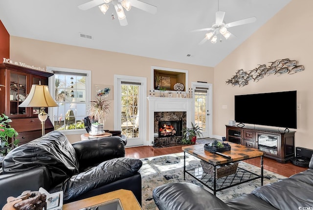 living room featuring ceiling fan, wood-type flooring, a premium fireplace, and high vaulted ceiling