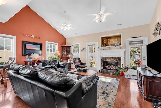 living room featuring ceiling fan, high vaulted ceiling, wood-type flooring, and a high end fireplace