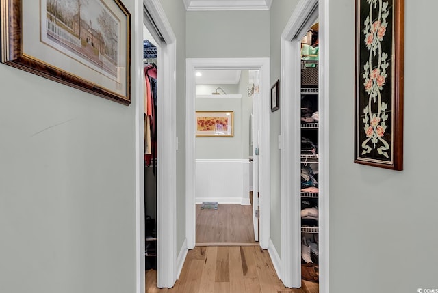 hallway with ornamental molding and light hardwood / wood-style floors