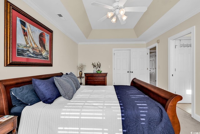 carpeted bedroom featuring ornamental molding, ceiling fan, and a tray ceiling