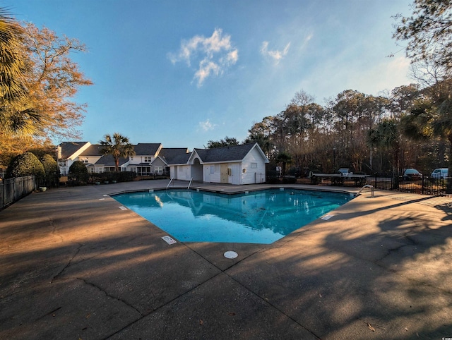 community pool featuring a residential view, fence, and a patio