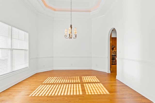 unfurnished dining area featuring wood-type flooring, ornamental molding, and a chandelier